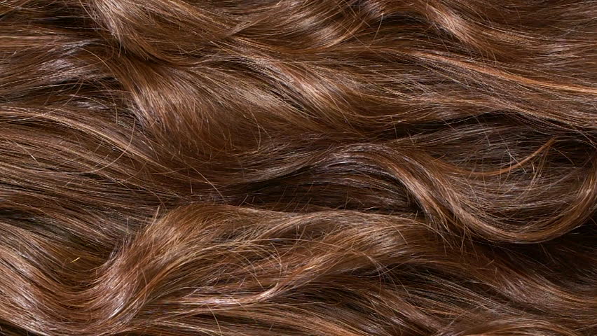 Close-up brown curly hair texture, female long hair background in slow motion
