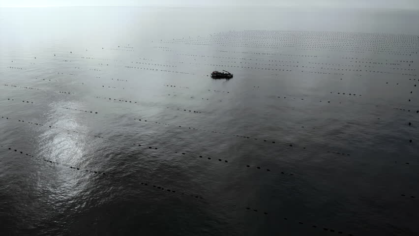 quiet sea voyage, lone boat drifts slowly over fogcovered sea with distant buoys and reflective waters