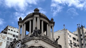Close-up of ornate Neoclassical architecture in Rio de Janeiro's historic center. Features a detailed clock, dome, and classical statues set against a modern city background and blue sky. - Powered by Shutterstock - Get 15% off with code: PIKWIZARD15