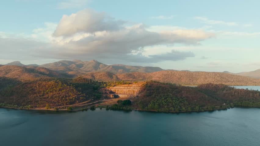 An aerial view reveals a serene mountain lake surrounded by rugged peaks, forests, and peaceful beauty.
