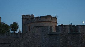 A stone turret of the Tower of London stands against the evening sky, with a half moon rising to the right and the historic battlements cast in soft twilight. - Powered by Shutterstock - Get 15% off with code: PIKWIZARD15