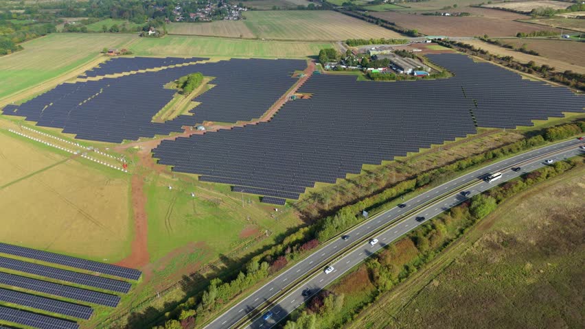 High altitude drone video of solar power station and highway traffic near Leicester, United Kingdom, summer day