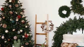 Decorated Christmas tree with ornaments and lights, evergreen garland, wreath, and ladder on white wall - Powered by Shutterstock - Get 15% off with code: PIKWIZARD15