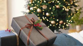 Wrapped gift boxes with ribbons tied on a couch near a lit Christmas tree with gold ornaments - Powered by Shutterstock - Get 15% off with code: PIKWIZARD15