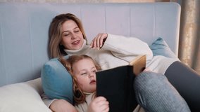 Mother and daughter lying on bed with pillows, relaxing together, child holding book while reading, mother smiling with eyes closed, cozy family bonding moment, warm atmosphere, tender connection - Powered by Shutterstock - Get 15% off with code: PIKWIZARD15