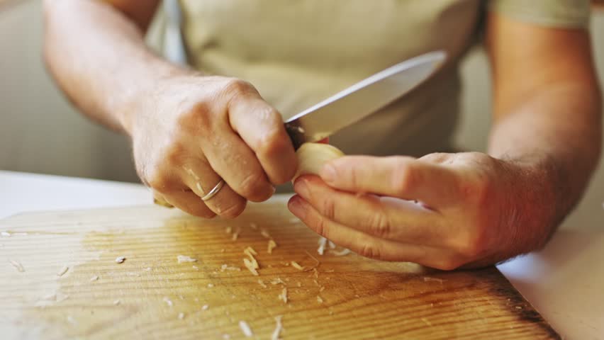 Male hands peeling garlic on a wooden cutting board