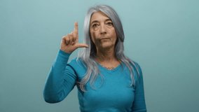 Senior grey-haired woman making loser gesture with fingers isolated over blue background, conveying playful and humorous expression in a studio setting. - Powered by Shutterstock - Get 15% off with code: PIKWIZARD15