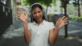Woman smiling wearing headphones outdoors on a city street showcasing joyful expression and casual vibe in urban daytime environment. - Powered by Shutterstock - Get 15% off with code: PIKWIZARD15