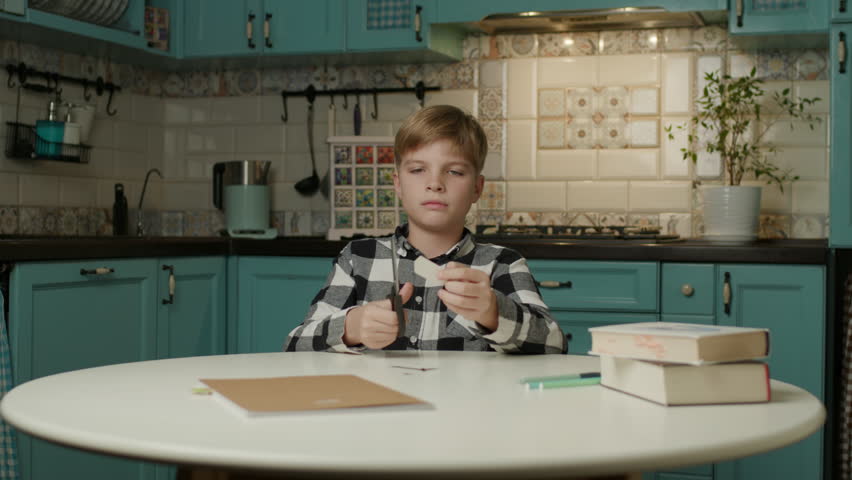 Boy Cutting Paper with Scissors at Home