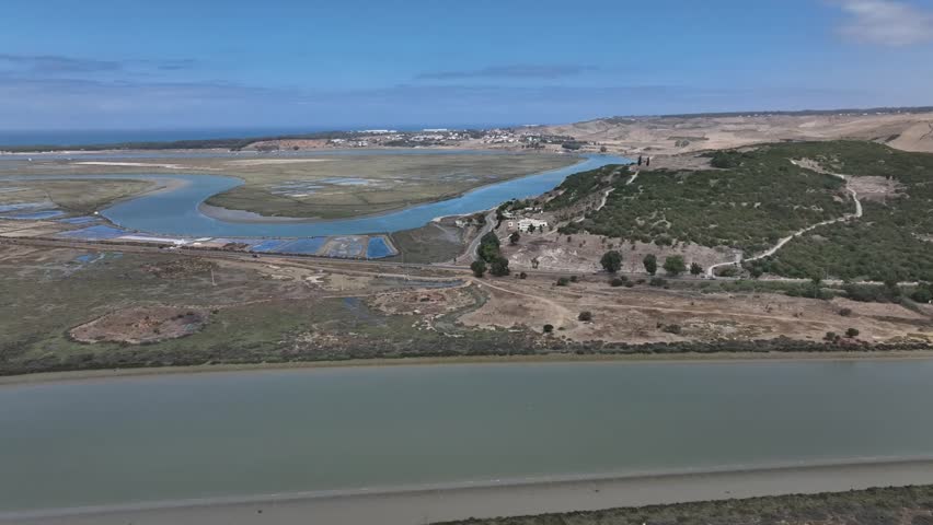 Cinematic drone shot capturing the mythical Lixus site and the twisting Loukkos River resembling a dragon, highlighting Morocco’s rich archaeological and legendary landscape.