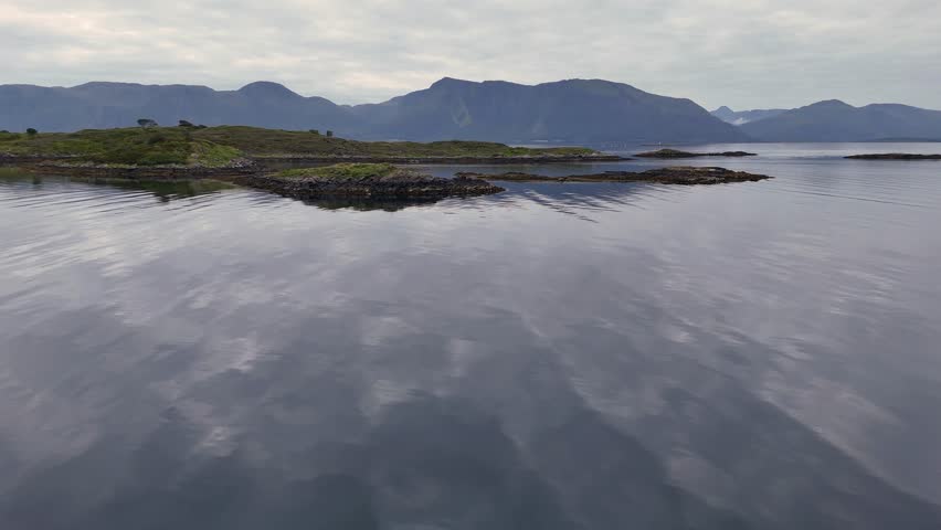 A Peaceful lake reflecting distant mountains and cloudy sky in calm natural setting