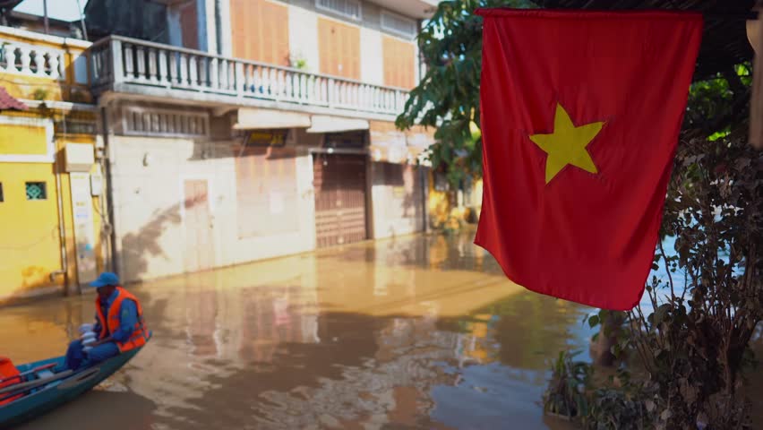 rescue team on boat in flooded city or town with buildings submerged in water, aid workers evacuate underwater village after heavy tropical rain or typhoon, climate change and global warming impact 4k