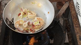 Close-up of fresh shrimp, scallops and squid being stir-fried in a flat pan with minimal oil, coarse chopped garlic and fresh red chili. Chef constantly tosses the pan for even cooking - Powered by Shutterstock - Get 15% off with code: PIKWIZARD15