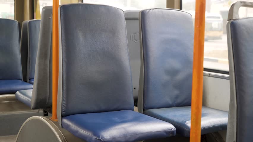 Empty blue seats and orange handrails in public transport in a trolleybus