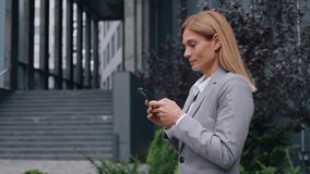 Smiling concentrated Caucasian adult business woman looking phone walking in city businesswoman internet addict scrolling social media mobile app female executive walk in downtown holding smartphone - Powered by Shutterstock - Get 15% off with code: PIKWIZARD15