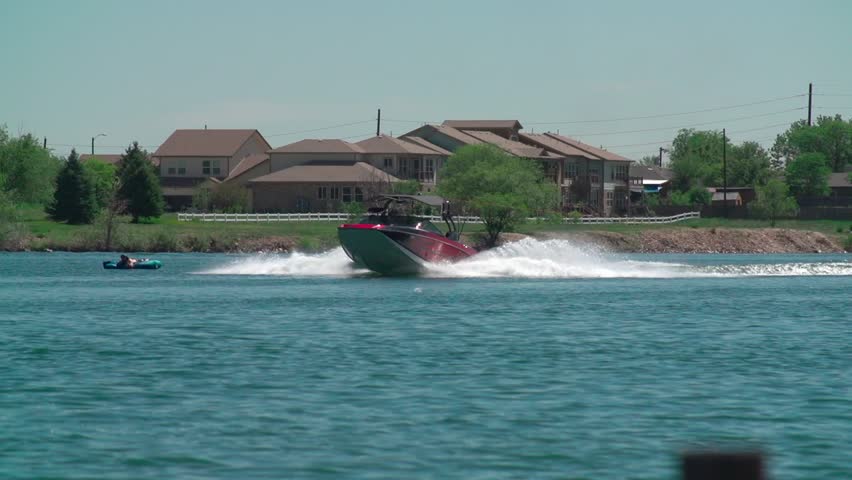 A slow-motion view of a person water skiing with a background of trees growing on a coast