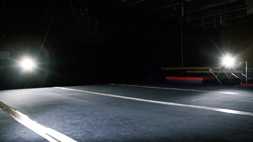 A strong young man demonstrates martial arts tricks against spotlights