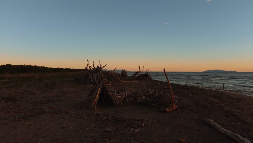 Peaceful evening twilight over Parco Maremma with driftwood tipi and pine forest along the sea beach