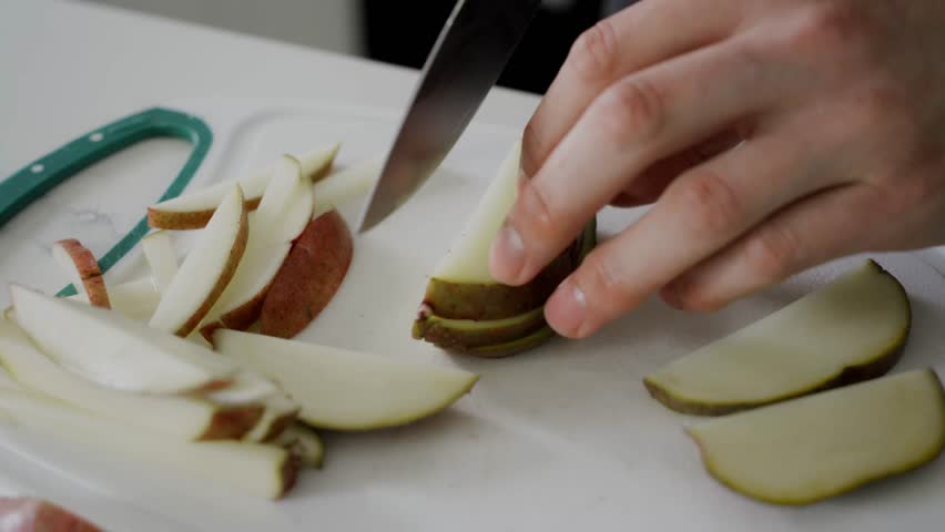 Cutting fresh potatoes with sharp knife as french fries garnish for serving Beef Qebapa dish.