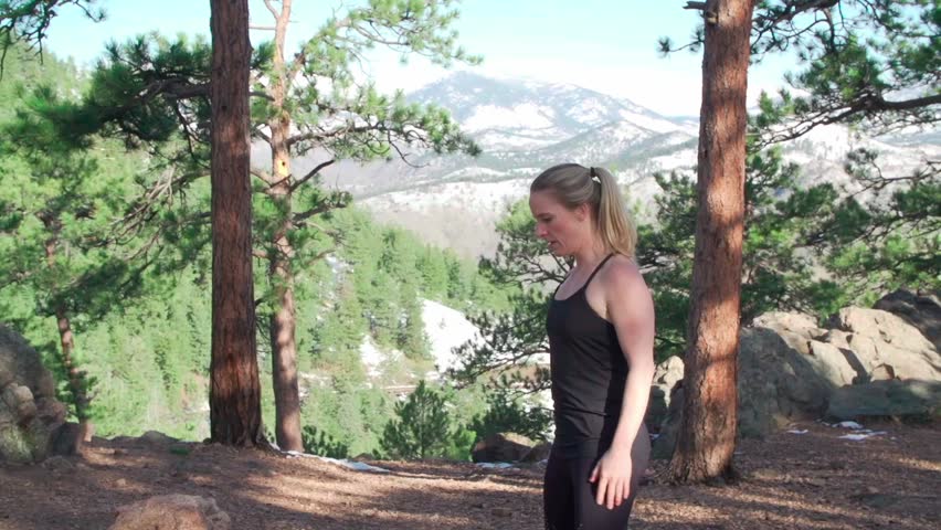 A female Caucasian fitness trainer working out with kettlebell weights outdoor in the park on a sunny day