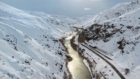 A shimmering river winds through a snowy canyon beside a railway line entering a tunnel, forming a dramatic and atmospheric winter landscape. - Powered by Shutterstock - Get 15% off with code: PIKWIZARD15