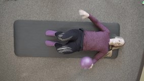 A top view of Caucasian female trainer explaining a workout exercise with resist-A-ball lying on yoga mat - Powered by Shutterstock - Get 15% off with code: PIKWIZARD15