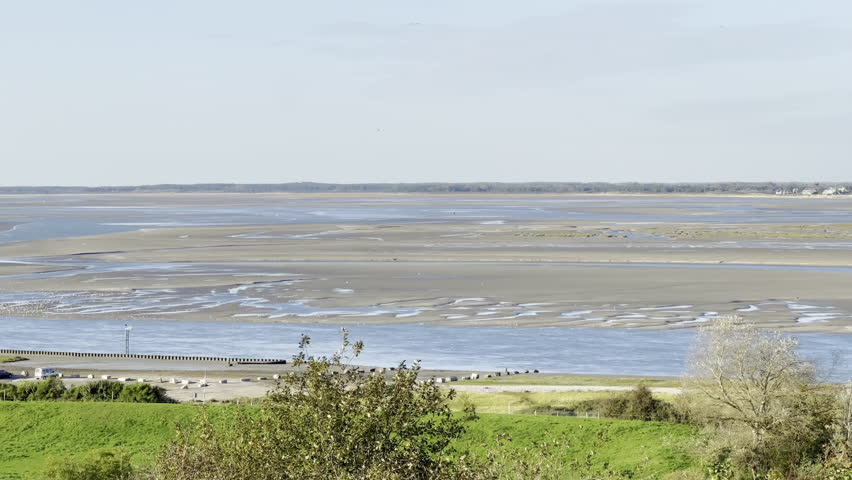 Cap Hornu panoramic vista across the Somme Bay at low tide from Saint-Valery-sur-Somme, showing winding tidal channels, broad sandbanks, marker buoys, seabirds and lush pastures beneath an autumn sky