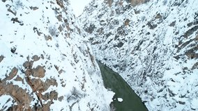 Aerial drone view of a narrow canyon with a river running between steep snowy cliffs. A dramatic and cinematic winter landscape. - Powered by Shutterstock - Get 15% off with code: PIKWIZARD15