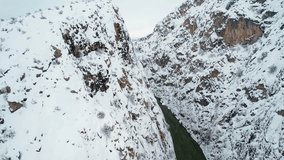 Aerial drone view of a narrow canyon with a river running between steep snowy cliffs. A dramatic and cinematic winter landscape. - Powered by Shutterstock - Get 15% off with code: PIKWIZARD15