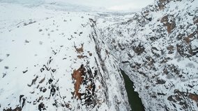 Aerial drone view of a narrow canyon with a river running between steep snowy cliffs. A dramatic and cinematic winter landscape. - Powered by Shutterstock - Get 15% off with code: PIKWIZARD15