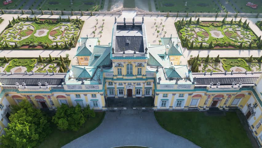Drone aerial footage of Wilanów Palace in Warsaw with baroque architecture, decorative facade, gardens and scenic morning sunlight highlighting historic royal landmark.