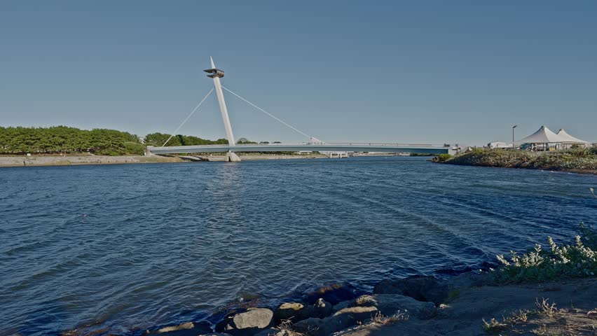The iconic Kasai Nagisa Bridge, designed like a sailboat mast, connecting the West Beach to the city under a vast Tokyo sky.