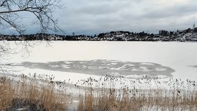 There is snow and ice on the frozen lake in Sollentuna, Sweden. The view of the bay in Edsviken outside Stockholm City in the winter season with a cloudy sky in the background. - Powered by Shutterstock - Get 15% off with code: PIKWIZARD15