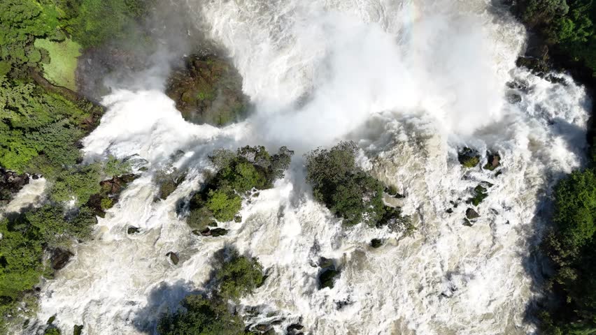 Drone top-down view of Binga Falls in Angola, showing the raw power of cascading water and mist surrounded by dense tropical forest in a remote African setting