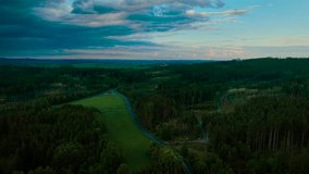 Curving road cutting through green forest under dramatic evening sky. Winding asphalt stretching across woodland and meadow. Narrow highway running between dense trees and open fields - Powered by Shutterstock - Get 15% off with code: PIKWIZARD15