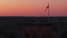 Aerial drone orbit captures the England flag waving atop St Albans Cathedral during sunset, with warm orange light and the city skyline creating a majestic and patriotic scene - Powered by Shutterstock - Get 15% off with code: PIKWIZARD15