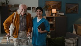 Medium shot of young woman as female nurse posing with white haired senior man using walker standing at home both smiling at camera, assisted living concept, copy space - Powered by Shutterstock - Get 15% off with code: PIKWIZARD15