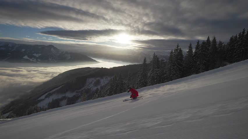 A Skier in a red uniform sliding down on a snow covered hill