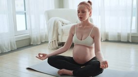 Pregnancy prenatal breathing. Pregnant woman with big belly sitting in lotus pose on yoga matt at home. Pregnant girl practicing yoga mindfulness meditation. Relaxation self care during pregnancy - Powered by Shutterstock - Get 15% off with code: PIKWIZARD15