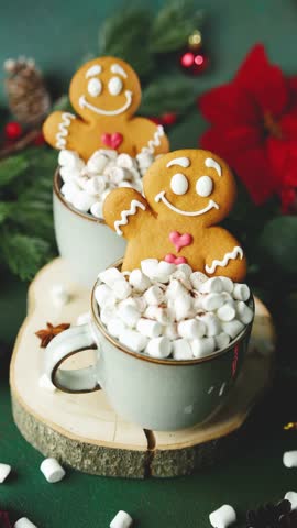 Two gingerbread men cookies sitting in cups filled with marshmallows and hot cocoa during winter.