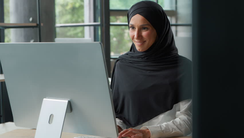 Happy Arabian business woman in hijab typing computer keyboard Muslim Islamic businesswoman female girl employer work smiling working online internet at table startup project developing use cyberspace - Powered by Shutterstock - Get 15% off with code: PIKWIZARD15