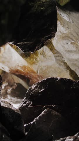 A relaxing vertical video recording of a sea cave with waves and rocks.