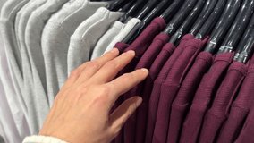 Hand touching soft ribbed knit shirts on clothing rack in retail store, selective focus on burgundy, grey color garments – shopping texture concept  - Powered by Shutterstock - Get 15% off with code: PIKWIZARD15