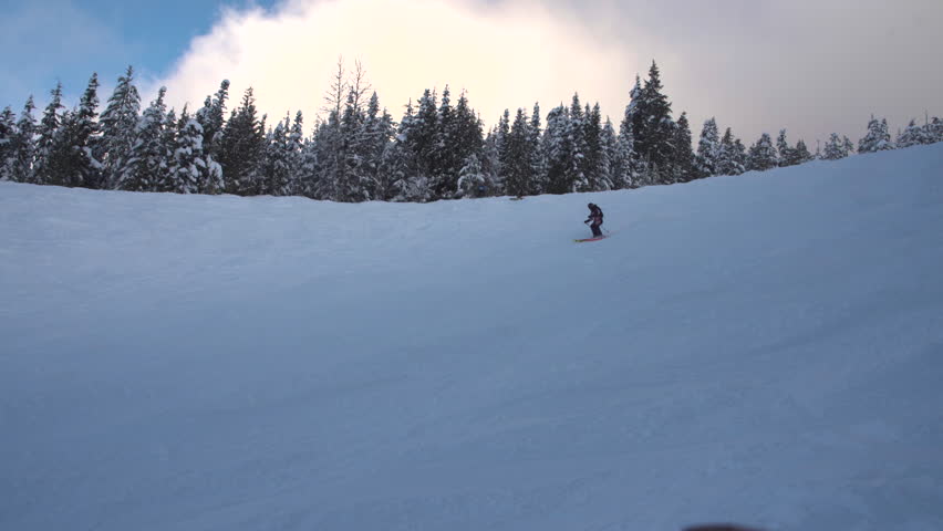 A skier skiing down a snowy mellow slope in whistler on a groomer