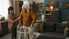 Slow motion shot of Latin American young woman assisting senior man trying to get up from couch at home using walker with shaking hands, copy space - Powered by Shutterstock - Get 15% off with code: PIKWIZARD15