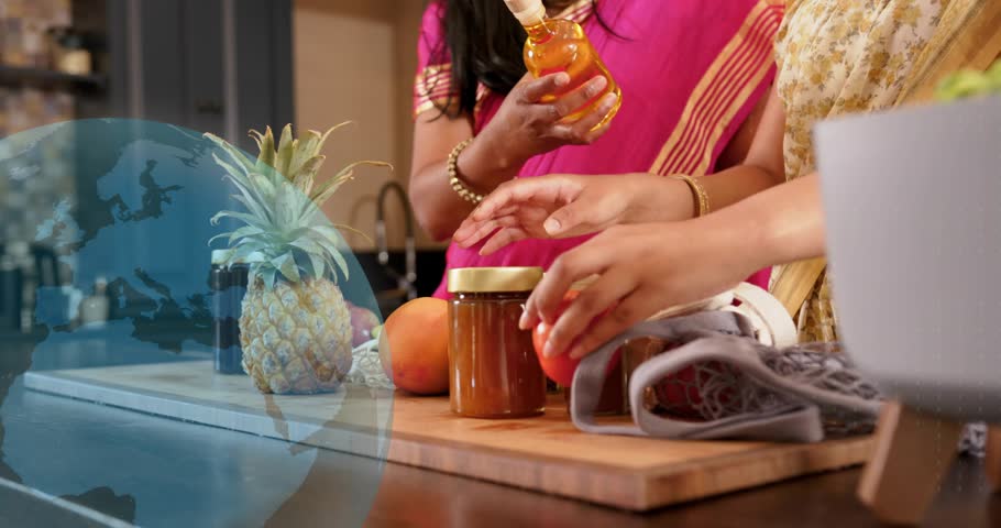 Mom lifting bottle while daughter packing jars on board, globe overlay guiding hands for food promo. Kitchen, pantry, produce, pineapple, sari, textiles, honey