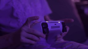 Young gamer hands hold white console controller in soft purple evening light during relaxed home indoors video game session - Powered by Shutterstock - Get 15% off with code: PIKWIZARD15