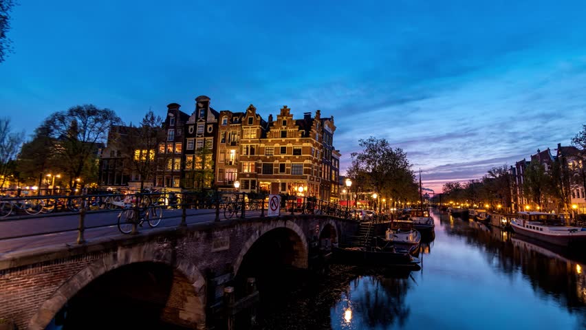 Amsterdam Netherlands time lapse city skyline day to night at canal waterfront