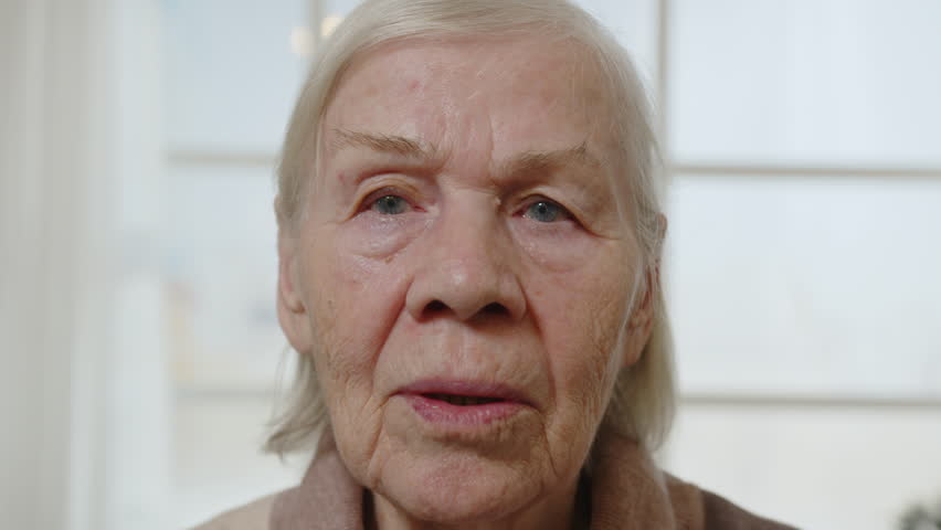 Portrait of old pensioner woman looking at camera.