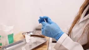 Unrecognizable doctor in a white lab coat and blue gloves preparing a syringe for injection in a clinic, focusing on aesthetic medicine - Powered by Shutterstock - Get 15% off with code: PIKWIZARD15